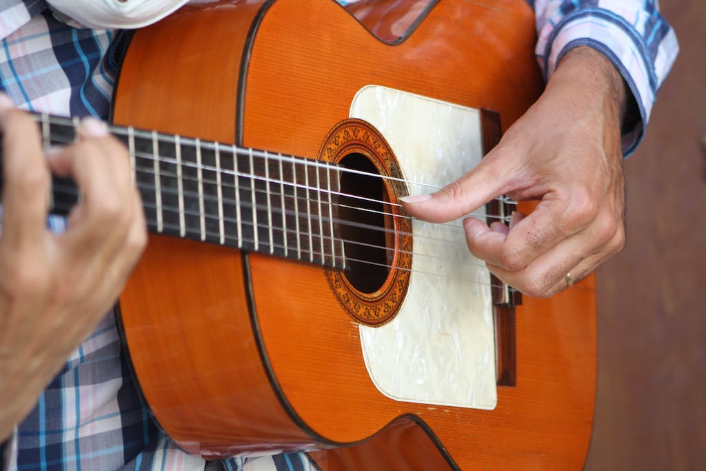 Person Playing Brown Acoustic Guitar
